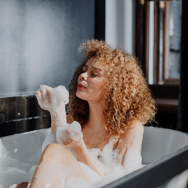 woman in bathroom sits in bubble bath
