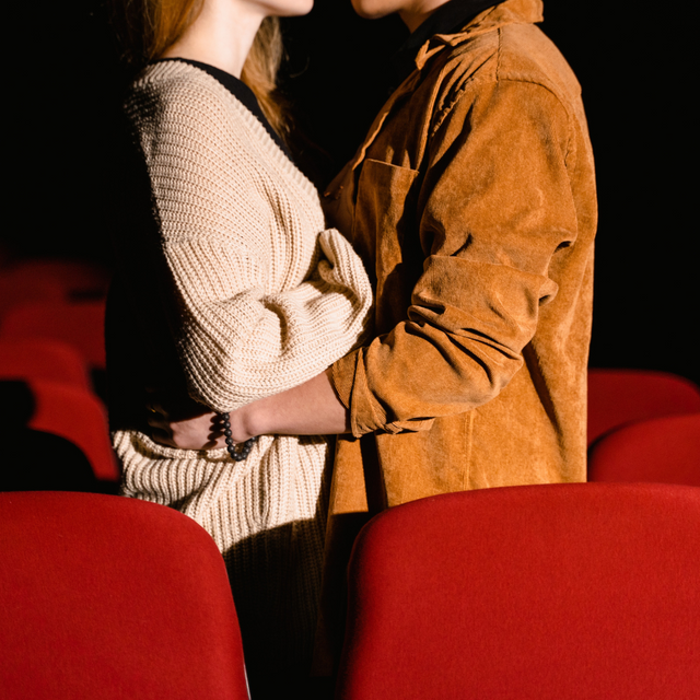 woman and man hugging closely in movie theater with red seats