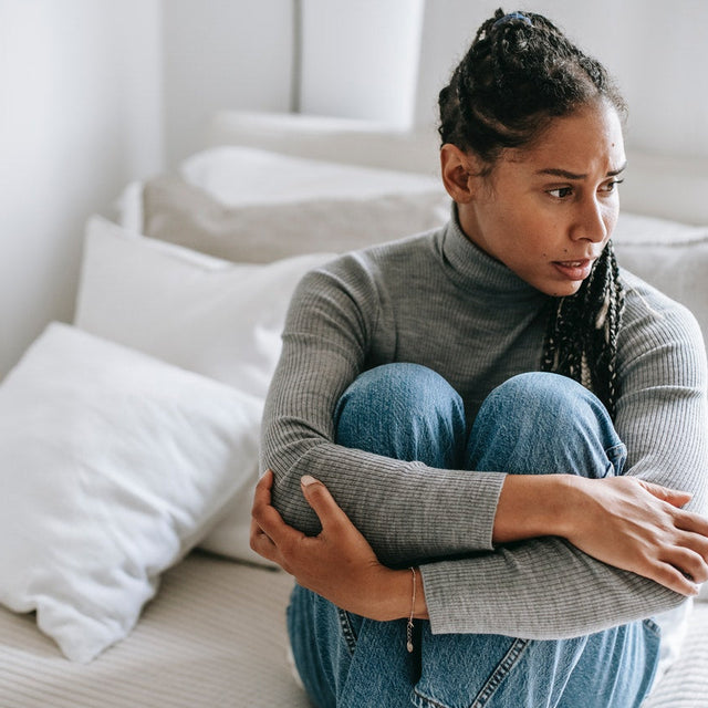 A woman having a stressful moment in bed worrying about if stress can cause a herpes outbreak.