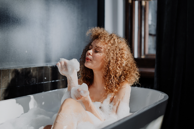 woman in bathroom sits in bubble bath