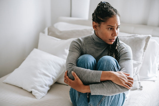 A woman having a stressful moment in bed worrying about if stress can cause a herpes outbreak.